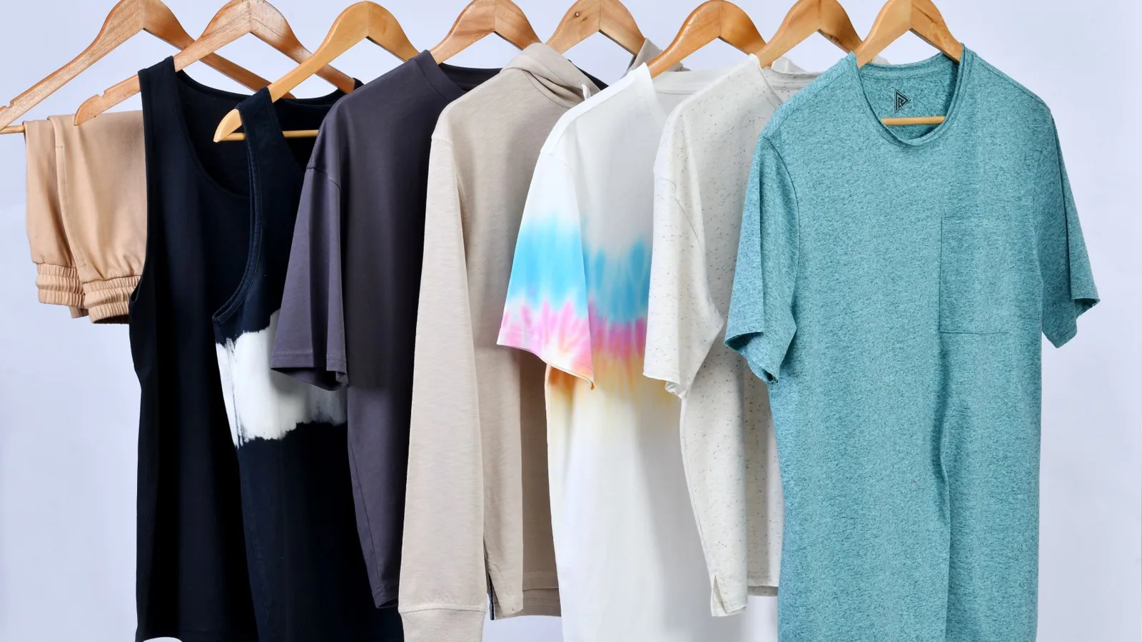 A variety of casual t-shirts on wooden hangers displayed in a minimalist style.