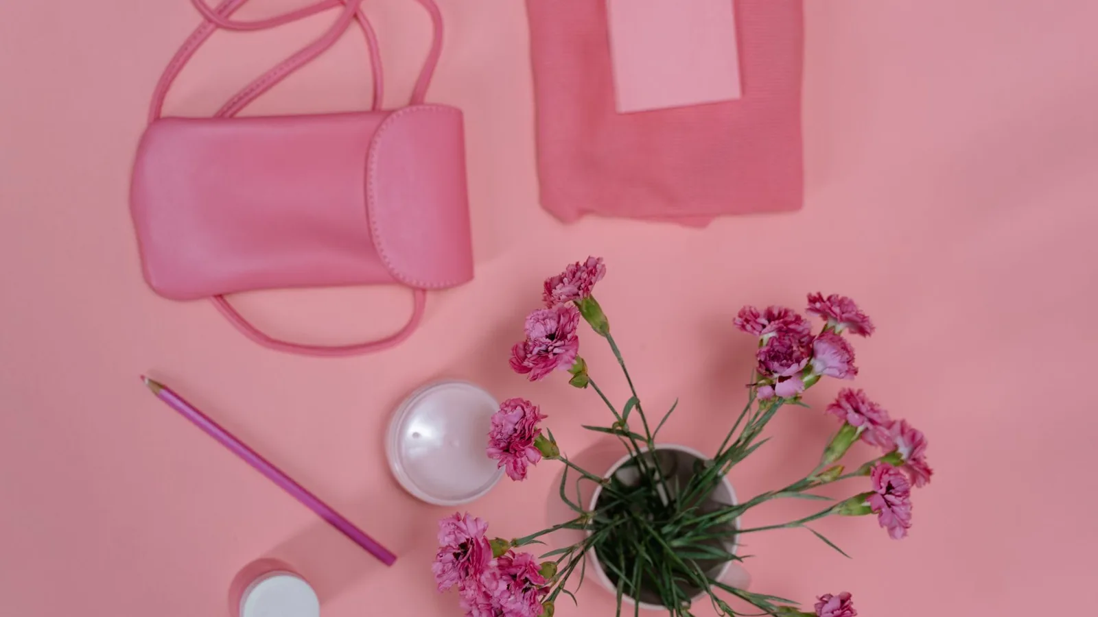 Stylish pink flat lay with flowers, accessories, and stationery on a vibrant background.