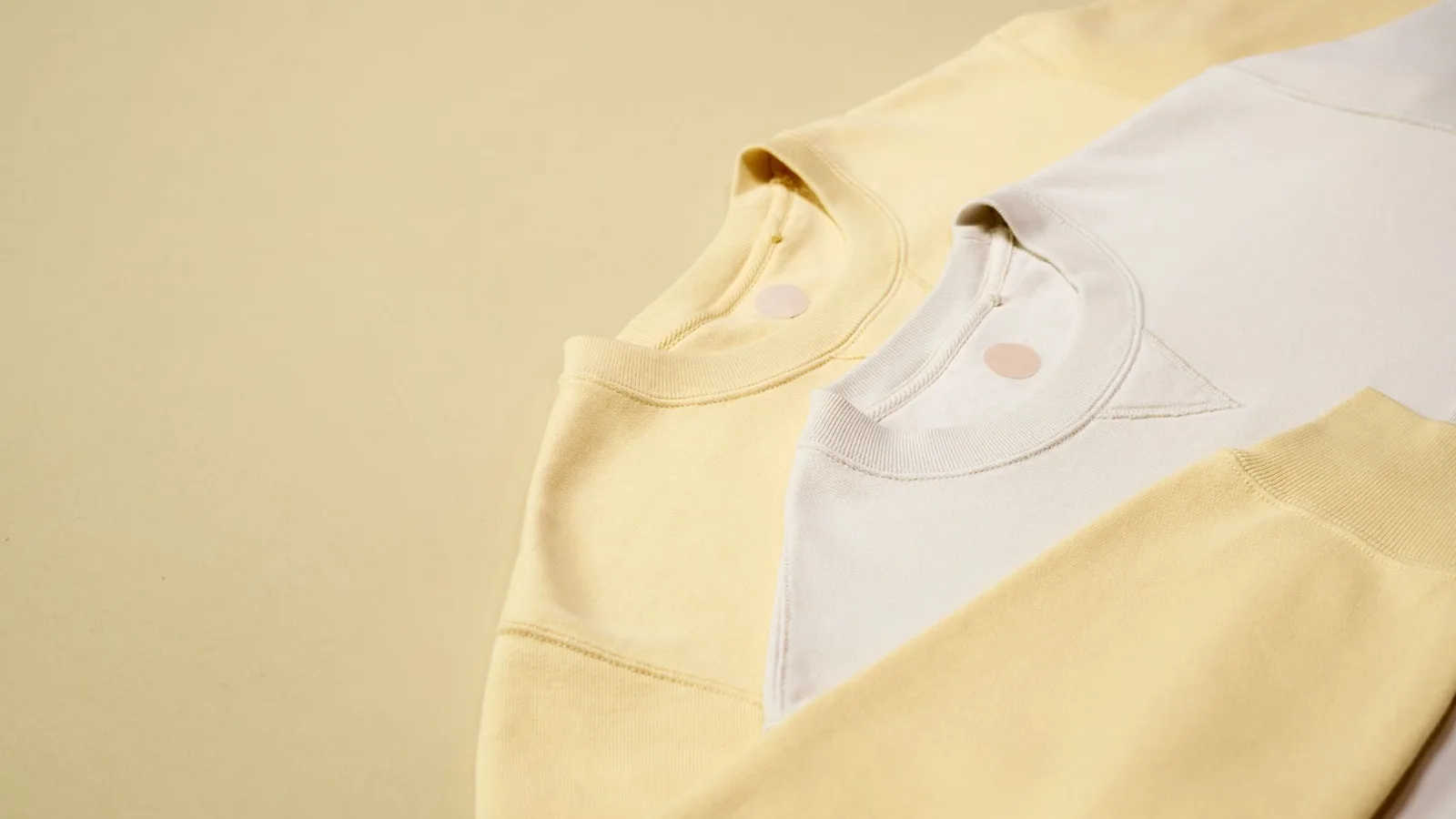 Pastel-colored sweatshirts arranged on a neutral background, emphasizing casual fashion style.